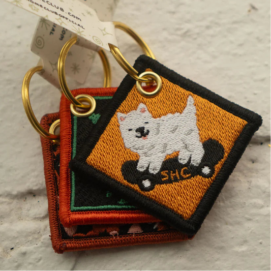 Embroidered keychain with a dog design on a textured surface